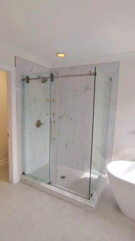 Frameless glass shower enclosure with marble tile walls in Chesapeake VA bathroom remodel