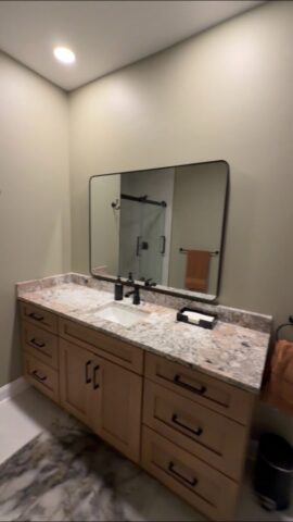 Bathroom renovation in Portsmouth Virginia featuring custom wood vanity, granite countertop and matte black fixtures